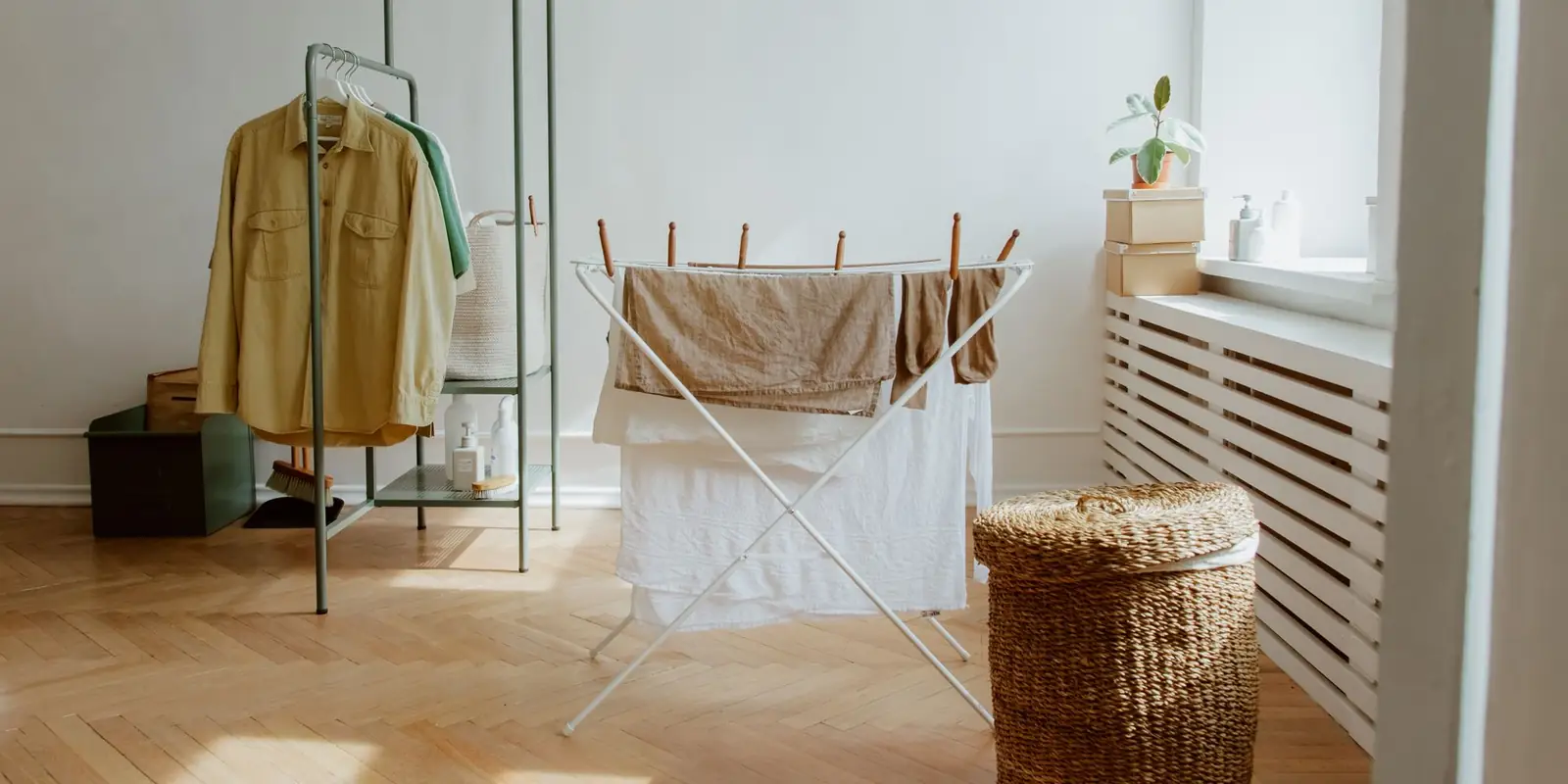 Washing drying on a folding airer next to a clothes rail in a bright room